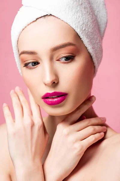 Beautiful young woman in white towel touching neck isolated on pink — Stock Photo