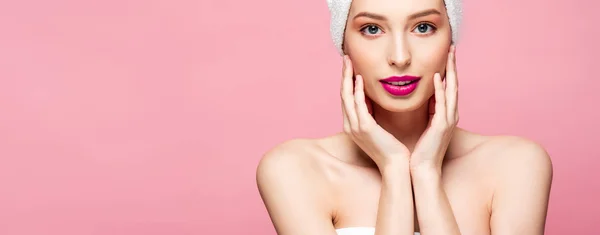 Panoramic shot of beautiful young woman in white towel touching face isolated on pink — Stock Photo