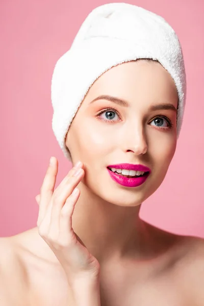 Young naked woman in white towel touching face isolated on pink — Stock Photo