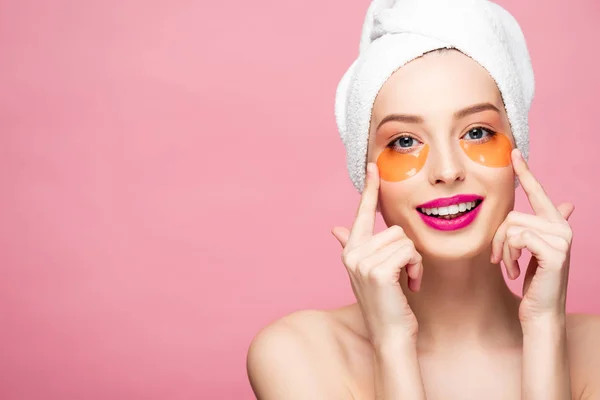 Chica desnuda feliz tocando la cara con parches para los ojos aislados en rosa - foto de stock