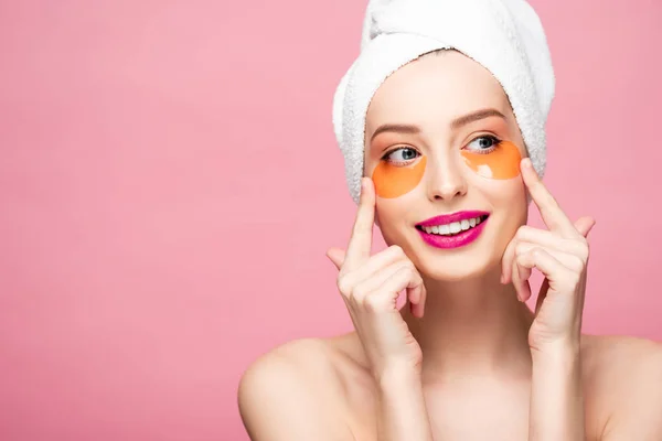 Alegre chica desnuda tocando la cara con parches para los ojos aislados en rosa - foto de stock