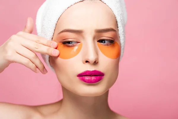 Bonita chica tocando la cara con parches para los ojos aislados en rosa - foto de stock