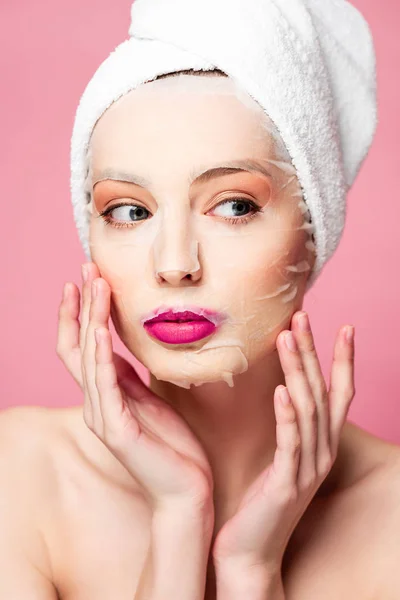 Молода гола жінка в масці для зволоження обличчя дивиться ізольовано на рожевий — стокове фото