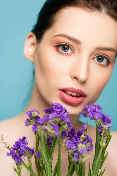 Jolie fille près de fleurs de limonium isolé sur bleu — Photo de stock