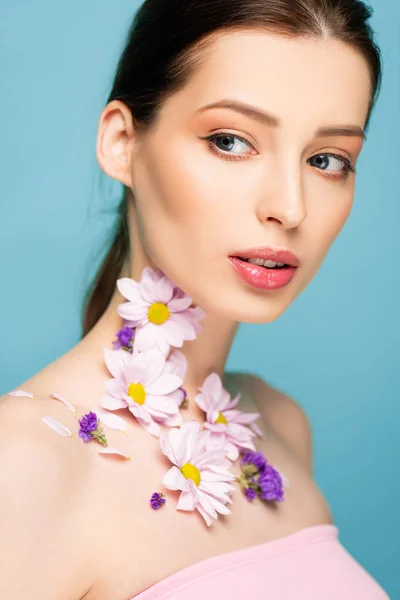 Giovane donna con fiori sul collo isolato su blu — Foto stock