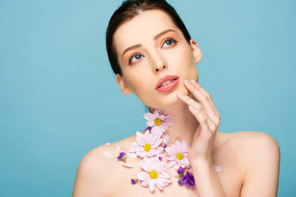 Jovem mulher nua com flores no pescoço toque rosto isolado no azul — Fotografia de Stock