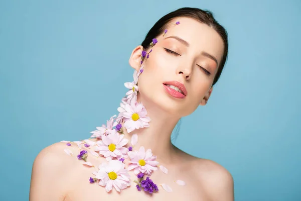 Nackte junge Frau mit Blumen und geschlossenen Augen isoliert auf blau — Stockfoto