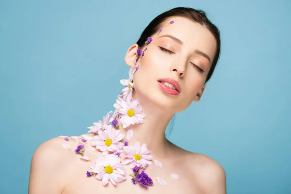 Jeune femme nue avec des fleurs et les yeux fermés isolé sur bleu — Photo de stock