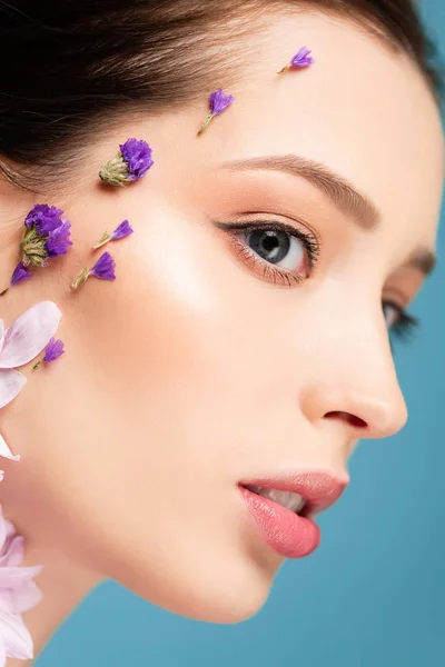 Nahaufnahme einer attraktiven Frau mit Blumen im Gesicht isoliert auf blauem Grund — Stockfoto