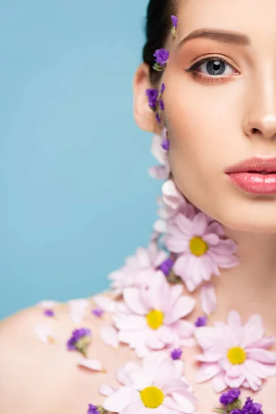 Vue recadrée de femme nue avec des fleurs sur le corps isolé sur bleu — Photo de stock