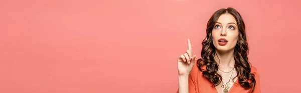 Plano panorámico de mujer joven reflexiva mostrando gesto de idea mientras mira hacia arriba aislado en rosa - foto de stock