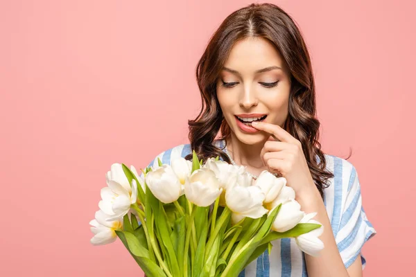 Glückliches Mädchen, das Lippe berührt, während es Strauß weißer Tulpen hält, isoliert auf rosa — Stockfoto