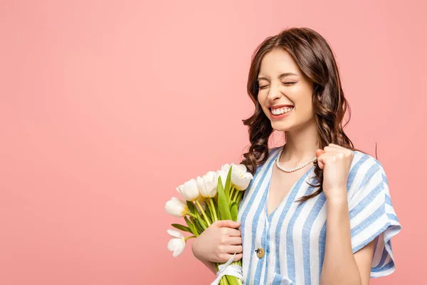 Ragazza eccitata mostrando sì gesto mentre tiene bouquet di tulipani bianchi isolati su rosa — Foto stock