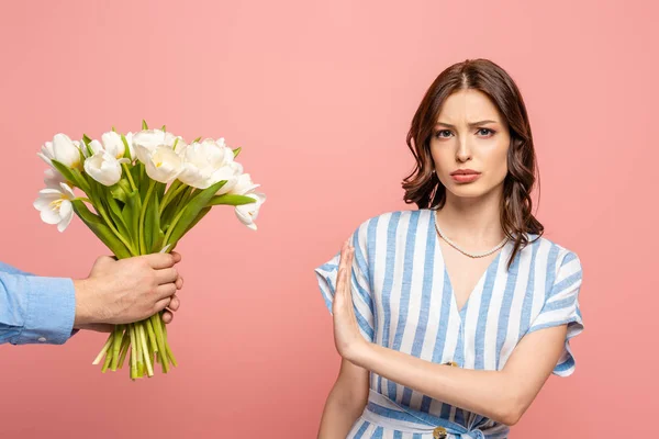 Частковий погляд людини, яка представляє букет білих тюльпанів незадоволеній дівчині не показує ніяких жестів ізольованих на рожевому — стокове фото