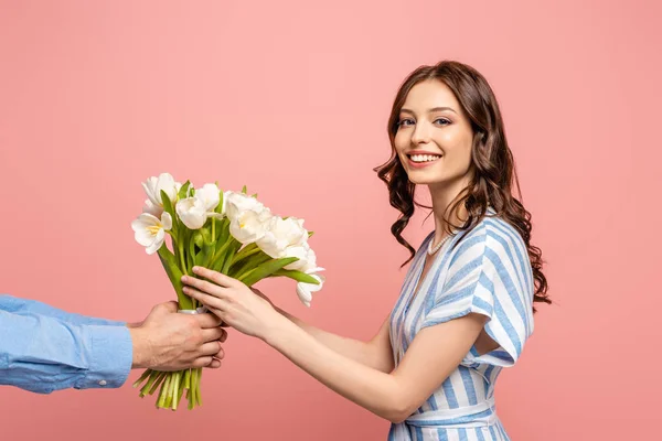 Vista cortada do homem apresentando buquê de tulipas brancas para alegre jovem mulher isolada em rosa — Fotografia de Stock