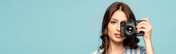 Fotografía panorámica de una atractiva joven mujer tomando fotos en cámara digital aislada en azul - foto de stock