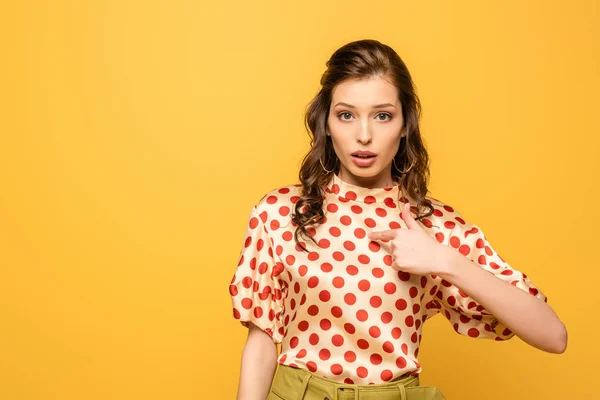 Shocked young woman pointing with finger at herself while looking at camera isolated on yellow — Stock Photo