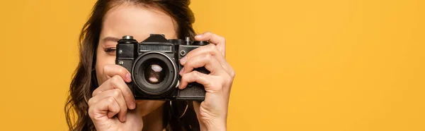 Scatto panoramico di giovane donna che scatta foto su macchina fotografica digitale isolata su giallo — Foto stock