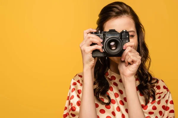 Young woman taking photo on digital camera isolated on yellow — Stock Photo