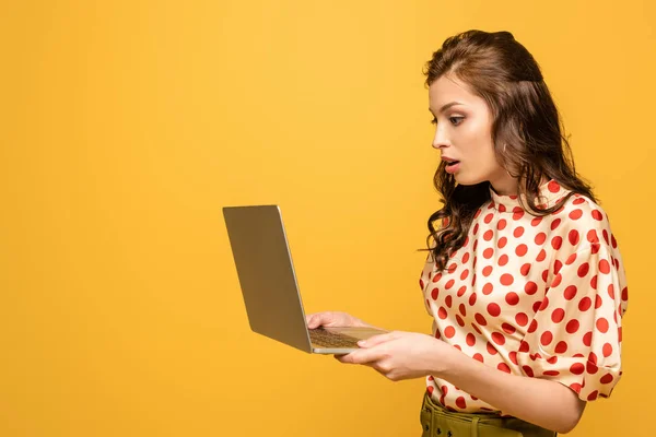 Sorprendió a la joven usando el ordenador portátil aislado en amarillo - foto de stock