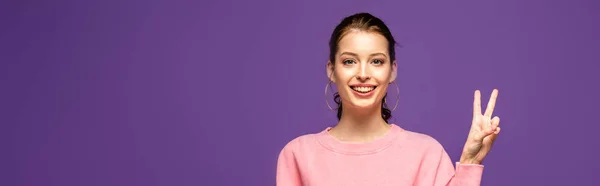 Панорамный снимок счастливой девушки, показывающей победный жест, изолированный на фиолетовый — стоковое фото