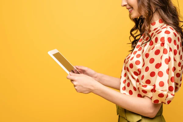 Обрізаний вид усміхненої молодої жінки з використанням цифрового планшета ізольовано на жовтому — стокове фото