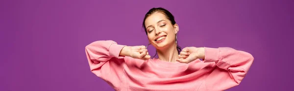 Plano panorámico de chica feliz estiramiento con los ojos cerrados aislados en púrpura - foto de stock