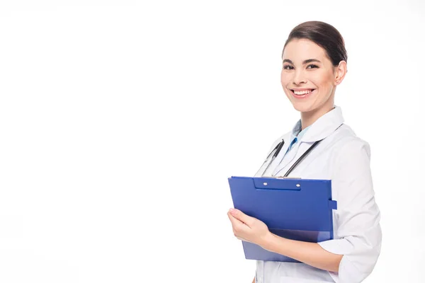 Schöne lächelnde Ärztin mit Stethoskop und Klemmbrett, die auf weiß isoliert in die Kamera blickt — Stockfoto