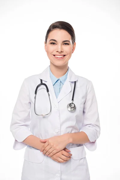 Atractivo médico en bata blanca y estetoscopio sonriendo a la cámara aislada en blanco - foto de stock