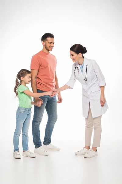 Full length of smiling pediatrician shaking hands with kid near father on white background — Stock Photo