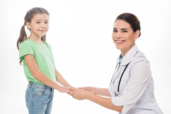 Pediatra sonriente y niño tomados de la mano y sonriendo a la cámara aislada en blanco - foto de stock