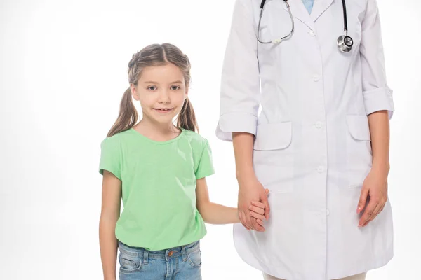 Niño sonriente mirando a la cámara mientras toma de la mano del pediatra aislado en blanco - foto de stock
