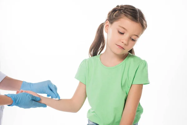Pediatrician with cotton wool rubbing hand of kid isolated on white — Stock Photo
