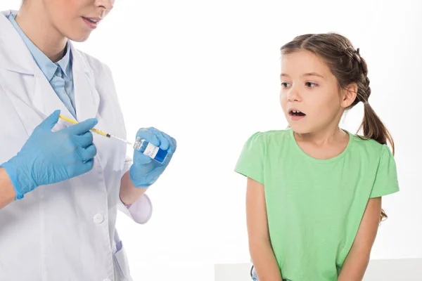 Pediatrician picking up flu vaccine in syringe near scared kid isolated on white — Stock Photo