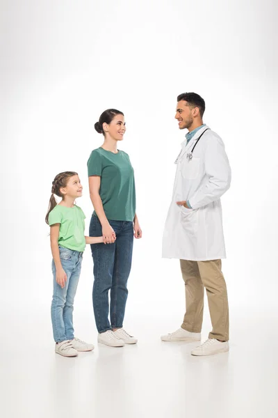 Full length of mother with daughter smiling at pediatrician on white background — Stock Photo
