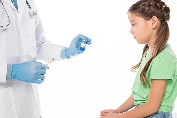 Вид збоку педіатра, який тримає вакцину проти грипу та шприц біля дитини, ізольовано на білому — стокове фото