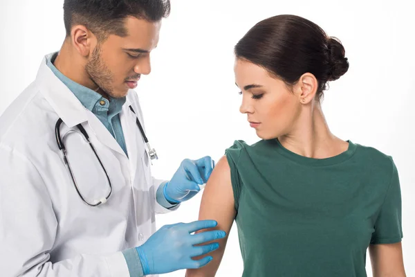 Médico guapo inyectando vacunas a una paciente aislada en blanco - foto de stock