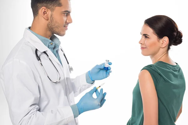 Усміхнений пацієнт дивиться на лікаря з вакциною проти грипу та шприцом ізольовано на білому — стокове фото