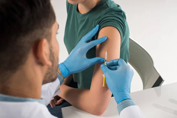 Selective focus of doctor doing vaccine injection in patient shoulder isolated on white — Stock Photo