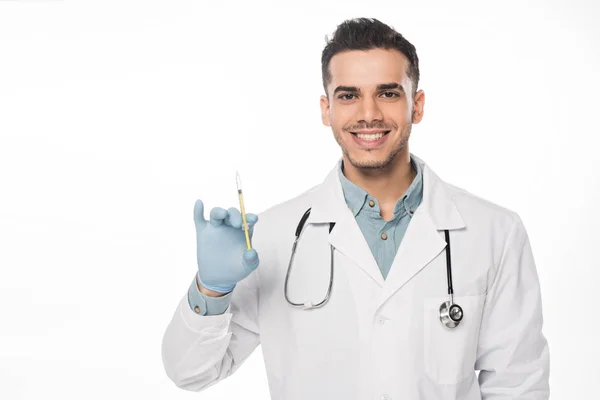 Handsome doctor holding syringe with vaccine and smiling at camera isolated on white — Stock Photo