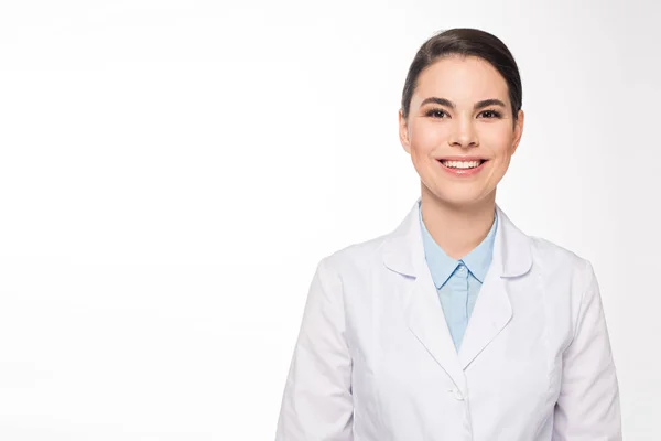 Hermoso médico en bata blanca sonriendo a la cámara aislada en blanco - foto de stock