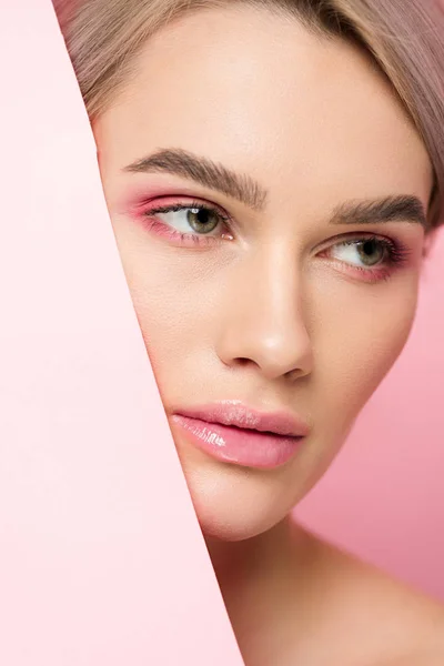 Attractive girl with pink makeup and piece of paper, isolated on pink — Stock Photo