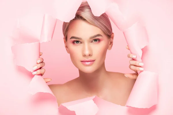 Bela menina nua com maquiagem rosa em papel rasgado, isolado em rosa — Fotografia de Stock