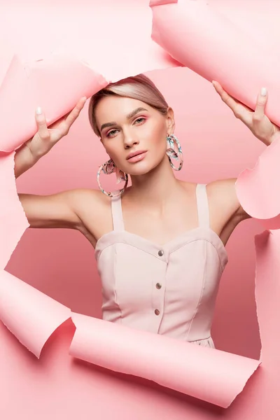 Привлекательная стильная девушка в розовом платье позирует в порванной бумаге, на розовом — стоковое фото