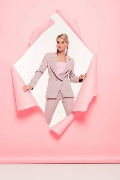 Fashionable girl in trendy suit posing in torn paper, on white — Stock Photo