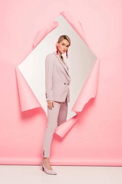 Beautiful girl in fashionable suit posing in torn paper, on grey — Stock Photo