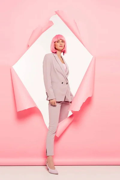 Fashionable beautiful girl in suit and pink wig posing in torn paper, on white — Stock Photo