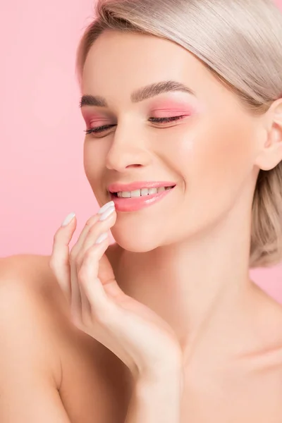 Счастливая нежная девушка с розовым макияжем, трогающая губы, изолированная на розовом — стоковое фото