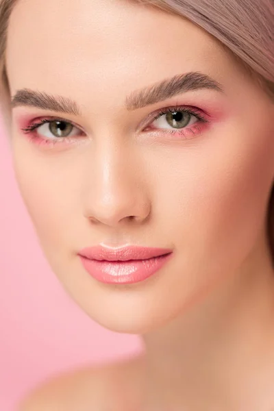 Chica atractiva con maquillaje rosa mirando a la cámara, aislado en rosa - foto de stock