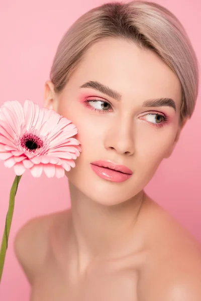 Ragazza nuda con trucco rosa e fiore gerbera, isolato su rosa — Foto stock